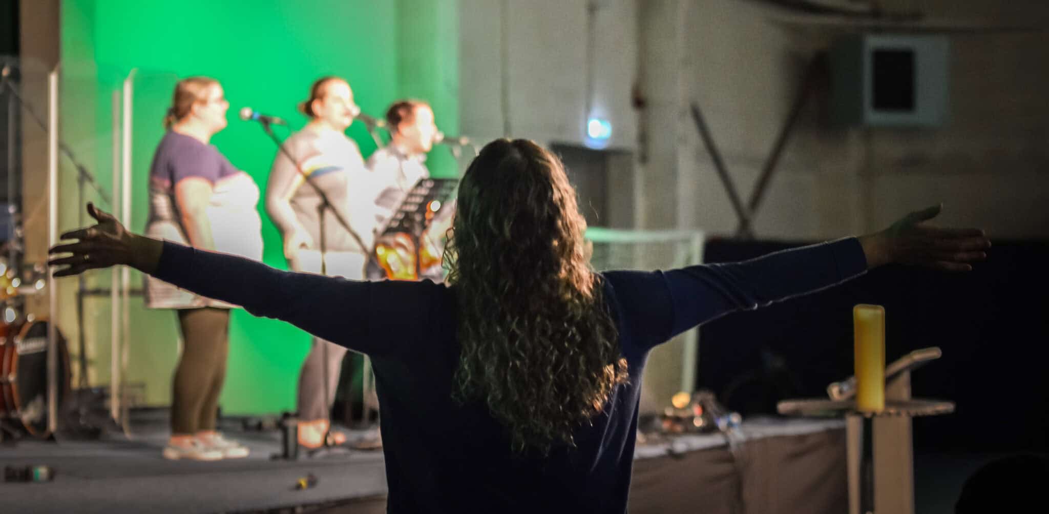A worshipper at St Thomas Philadelphia with the worship team in the background